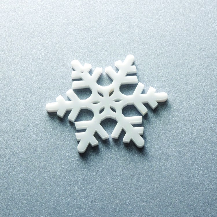 A set of laser cut white acrylic Christmas ornaments.